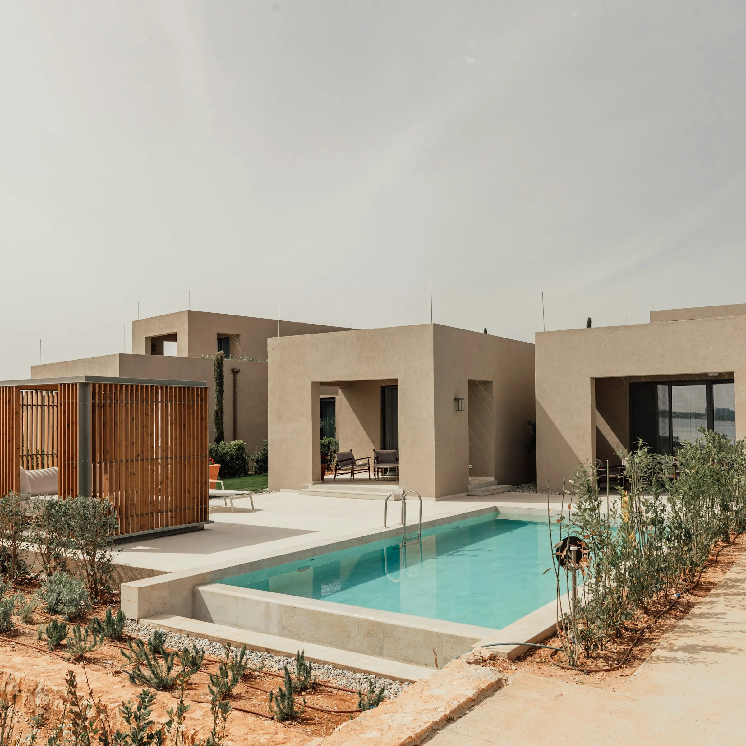Volumes enduits couleur ocre autour d’une piscine, brise-soleil en bois, Ramatuelle